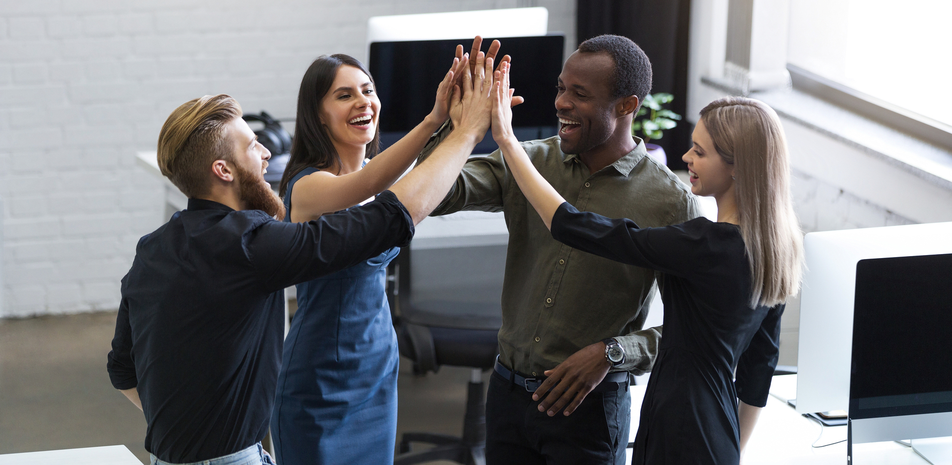 Group of young colleagues giving each other a high five